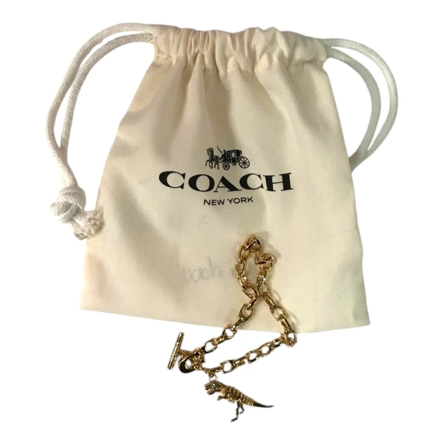 PULSERA COACH SKELETAL REXY CON DIJE DE DINOSAURIO – TONO DORADO NUEVO. — imagen 2