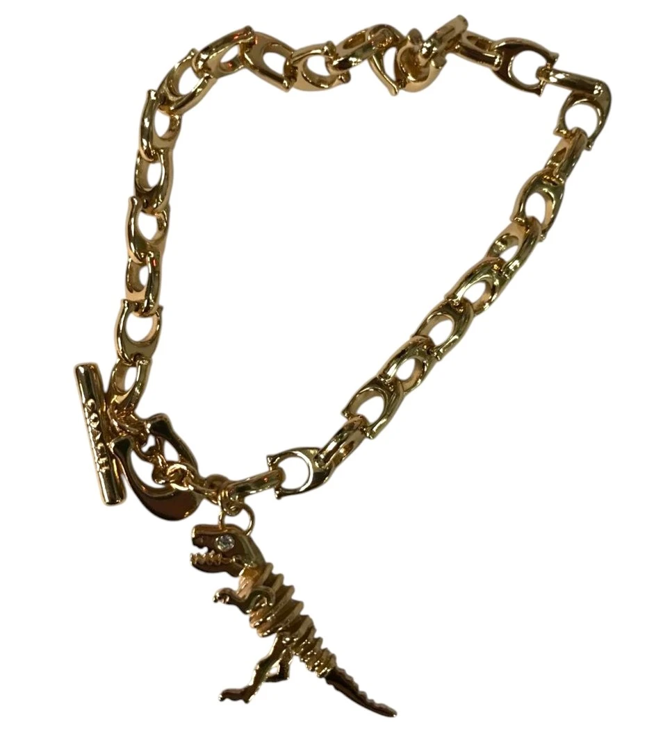 PULSERA COACH SKELETAL REXY CON DIJE DE DINOSAURIO – TONO DORADO NUEVO. — imagen 3