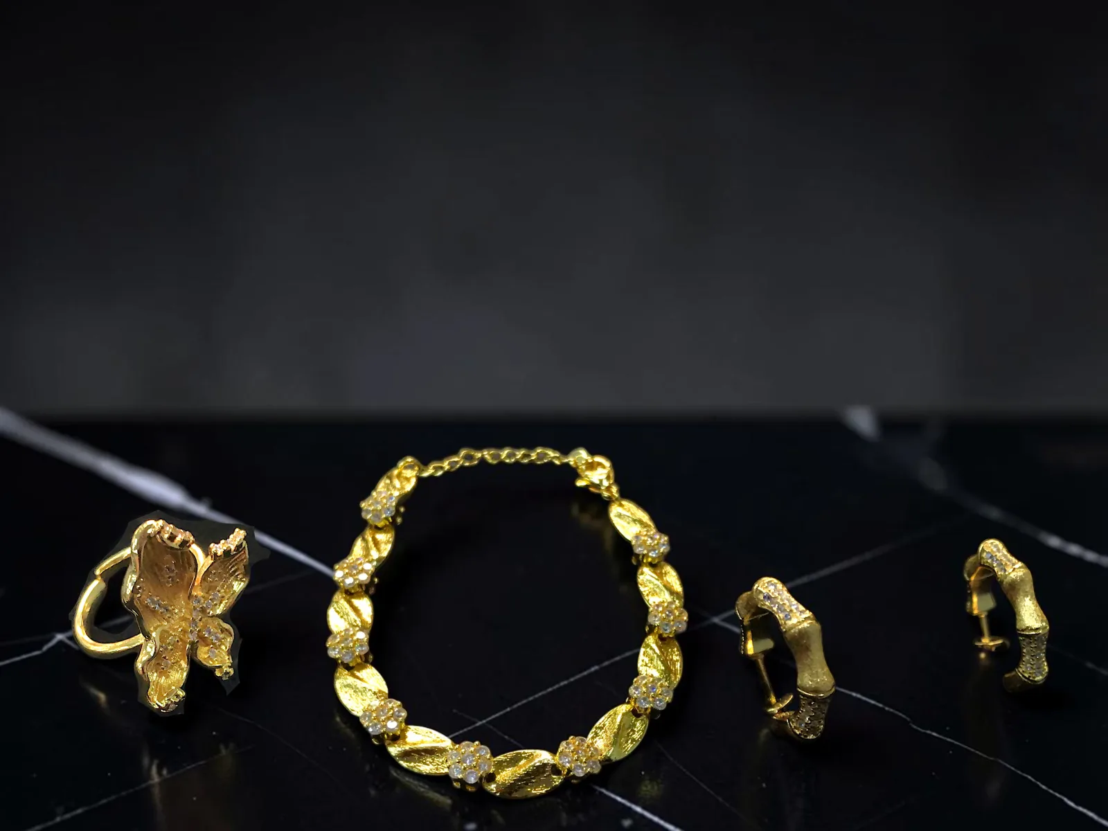 ANILLO CON FIGURA TRIDIMENSIONAL DE ALAS - PENDIENTES TIPO ARGOLLA - PULSERA DE ESLABONES,  JOYERÍA  FINA EN  CHAPA  DE ORO CON INCRUSTACIONES  DE ZIRCONIAS.